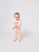 Load image into Gallery viewer, Baby wearing a white outfit with orange graphics on a white background