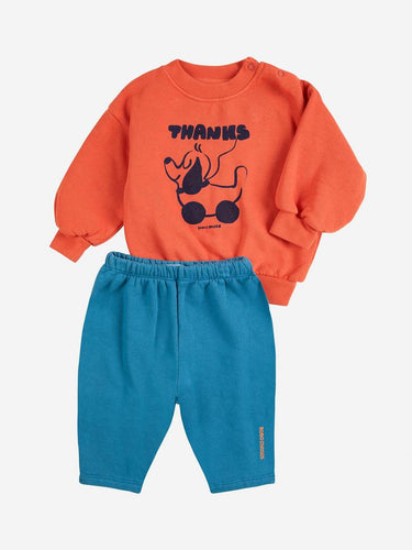 Orange sweatshirt with black graphic and blue pants on a white background