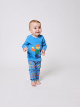 Load image into Gallery viewer, Child wearing blue pajama set with colorful designs on a white background