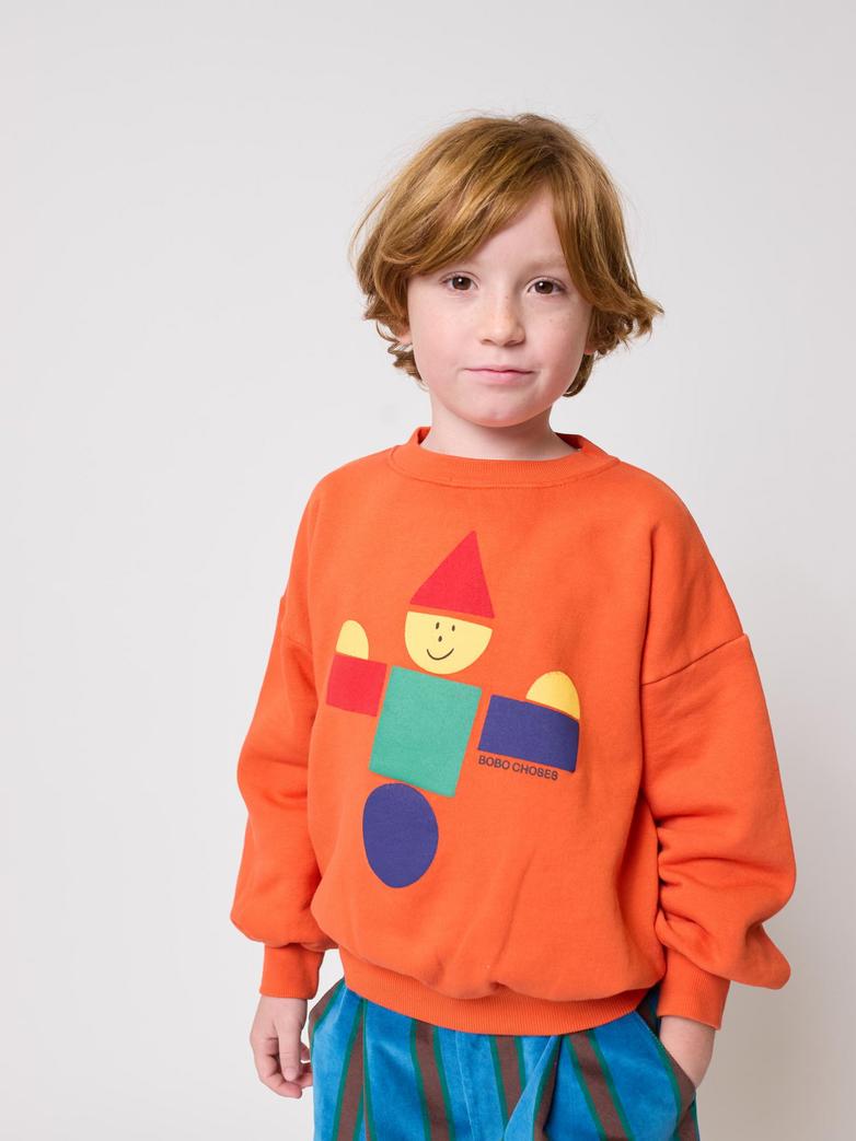 Child wearing an orange sweatshirt with a colorful graphic design on a white background